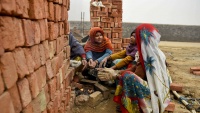 Žene radnici griju se uz vatru u Indiji.