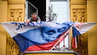 Muškarac lijepi poster Vladimira Putina, kandidata predsjedničkih izbora, na balkonu svoje kuće u  Moskvi