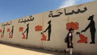 Jedna iračka djevojčica prolazi pored zida koji prikazuje zločine DAIŠ-a u Muselu