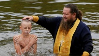Jedan pravoslavni svećenik pokrštava dijete u Krasnojarsku u Rusiji