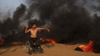 Palestinski invalid u kolicima baca kamenice prema izraelskim vojnicima