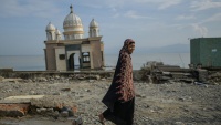 Žena prolazi ispred džamije oštećene u cunamiju i zemljotresu u Indoneziji